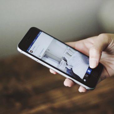 A hand holding a phone looking at social media.  