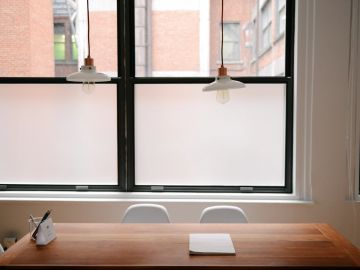 Minimalist workspace with wooden table and frosted window.