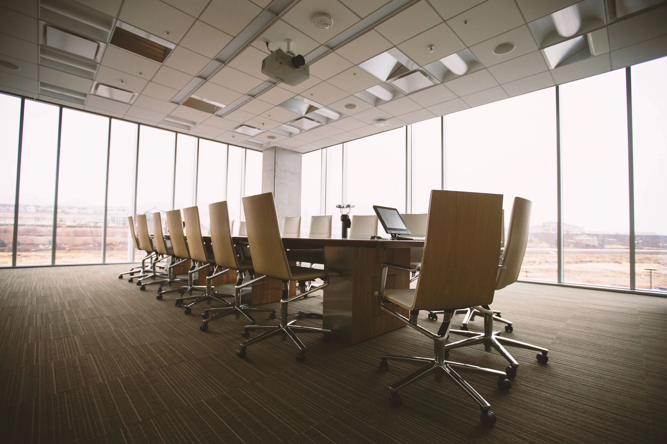 Modern conference room with wooden chairs and large windows.