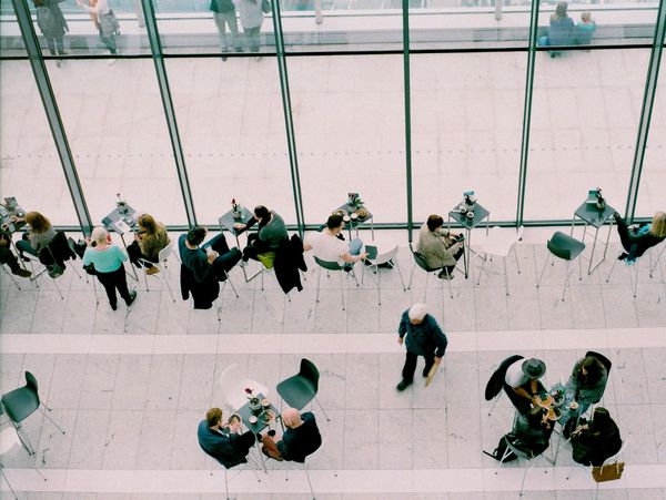 Overhead view of people seated and walking in a modern cafe.