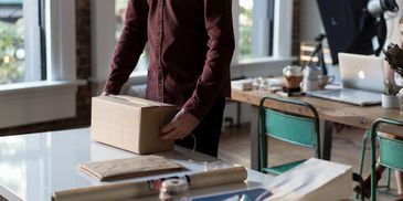 Person packaging a box in a workspace.