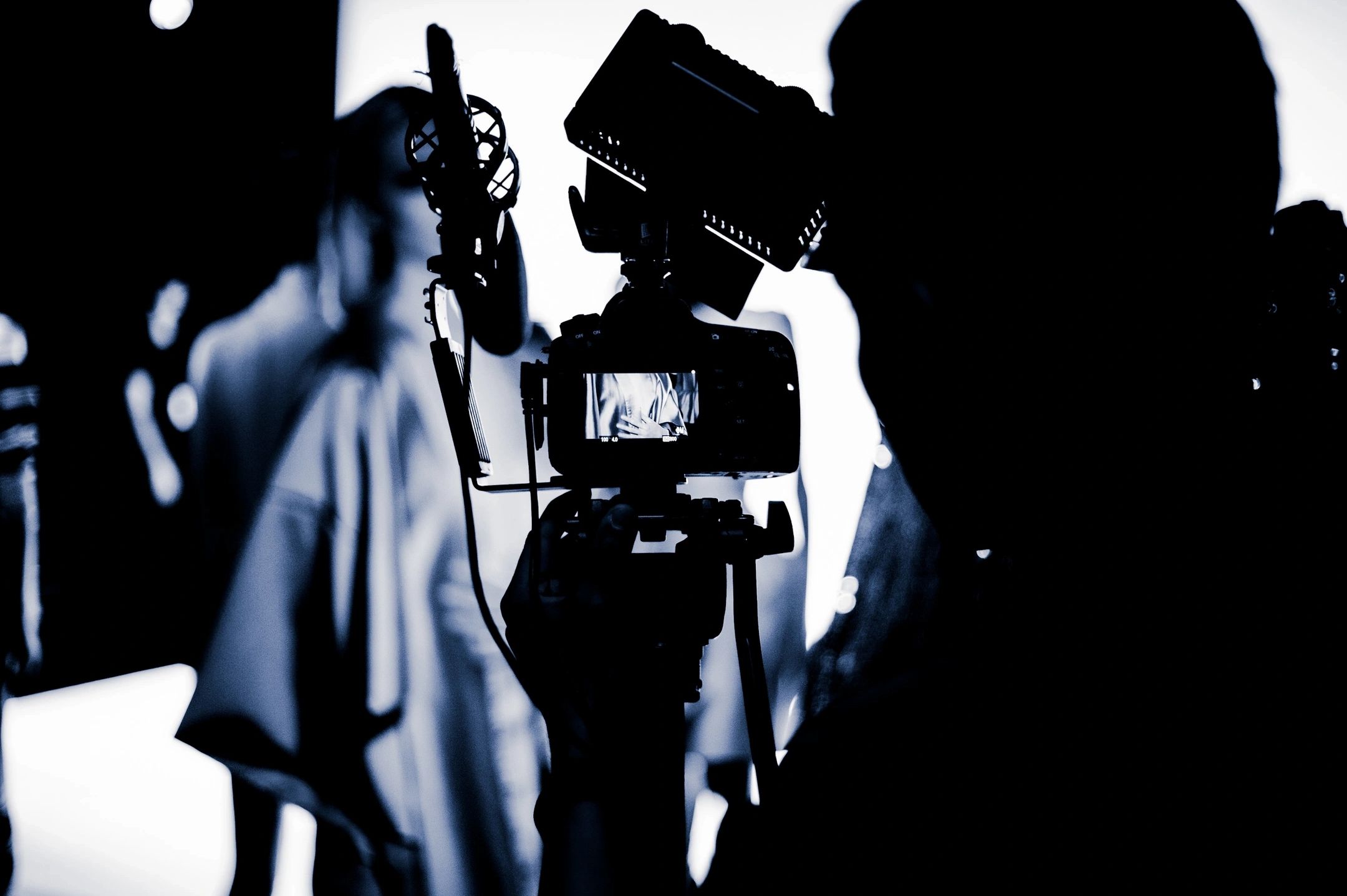 Silhouette of a camera filming a person in a studio setup.