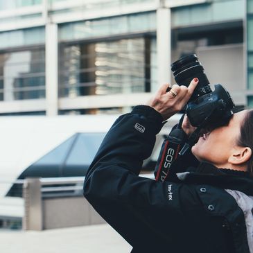Photographer capturing a shot with a DSLR camera in an urban setting.