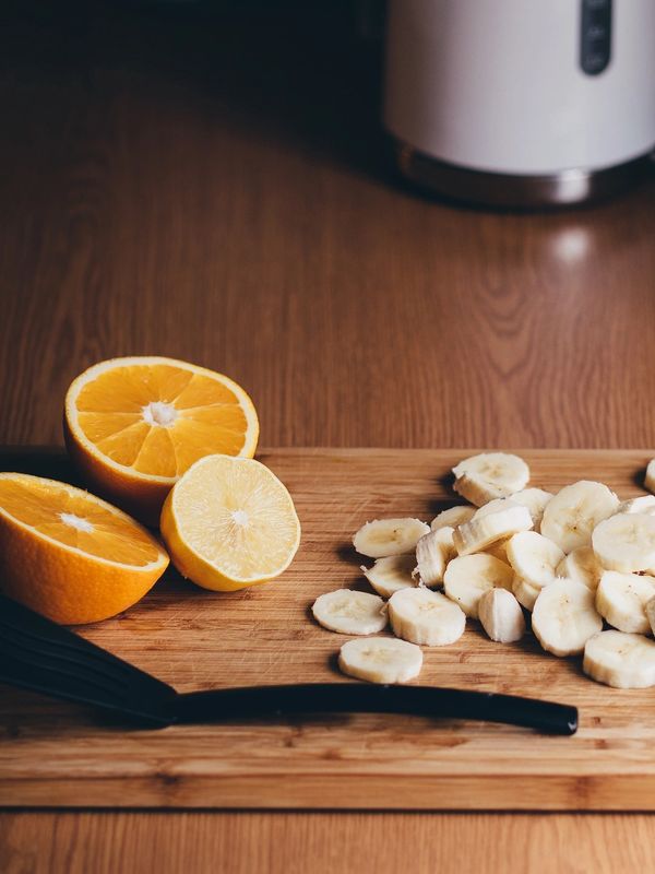 Sliced bananas and citrus fruits on a wooden cutting board.