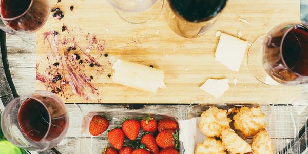 Overhead shot of charcuterie board with wine, cheese, meat, strawberries, and coconut macarons.