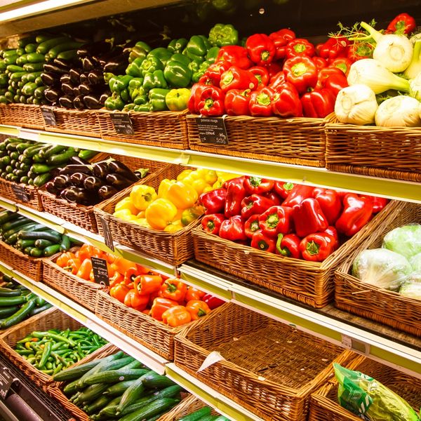 Colorful bell peppers and fresh vegetables neatly arranged on market shelves.