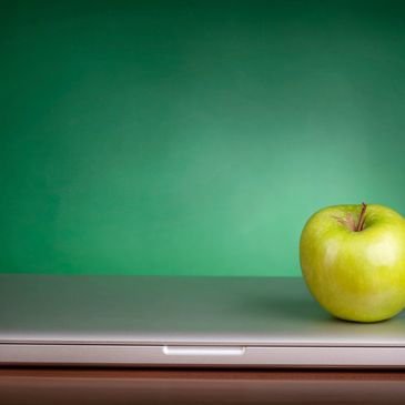 A green apple on top of a laptop