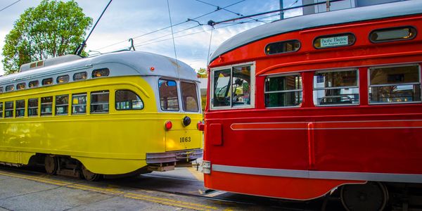 Yellow and red vintage streetcars on tracks.