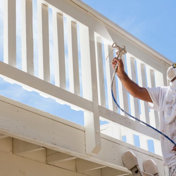 A painter painting the fence in white color