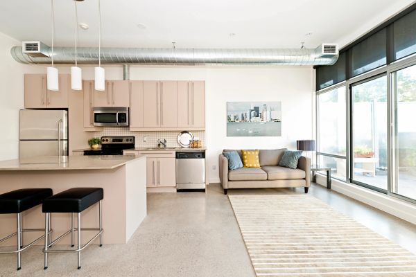 Bright modern kitchen and living area with large windows and neutral decor.