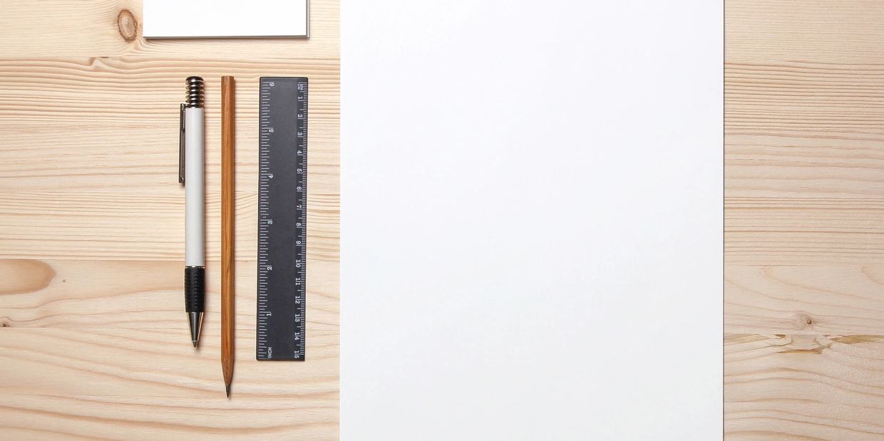 A piece of blank paper with a ruler, pencil, pen, and stack of blank index cards on the left.
