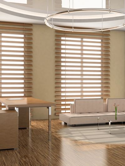 Modern office space with beige furniture and wooden blinds.
