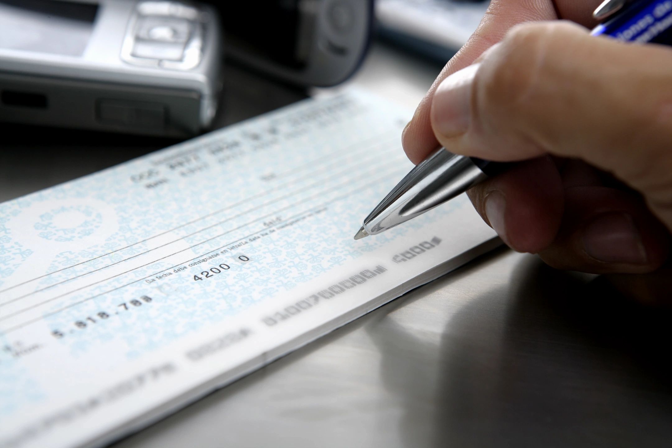 A person is writing a check with a pen