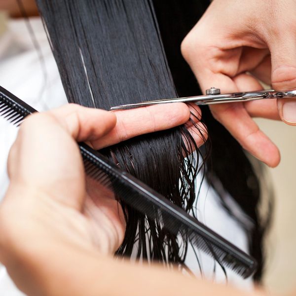 Woman with long, dark hair receiving hair cut. 