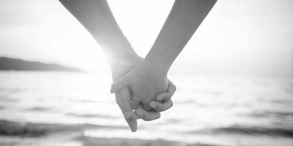 Black and white photo of a couple holding hands at the beach