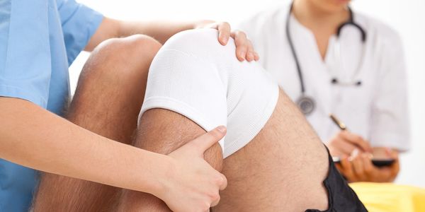 Physical therapist treating patient's knee injury.