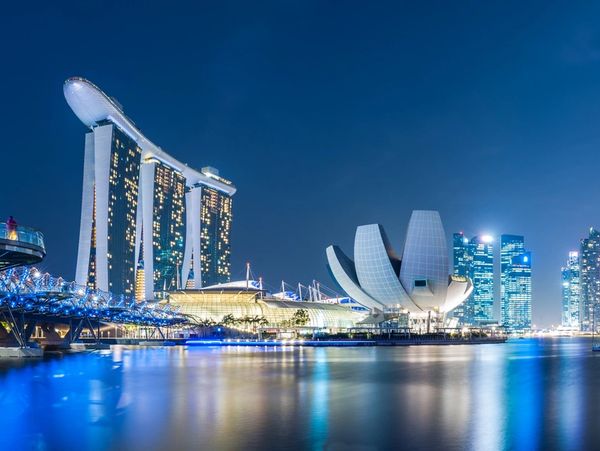 Night view of Marina Bay Sands and Artscience Museum in Singapore with reflections on water.