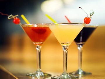 Three Martini glasses sit on top of a table filled with fresh vodka and gin martinis.