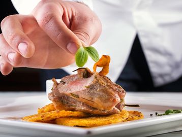 Chef garnishing a gourmet dish with fresh herbs.