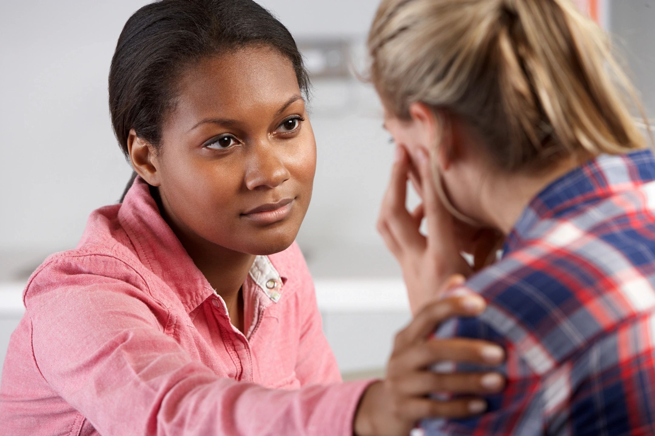 woman with hand on shoulder comforting another woman