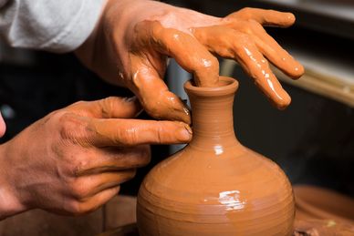 Hands shaping clay on a pottery wheel.
