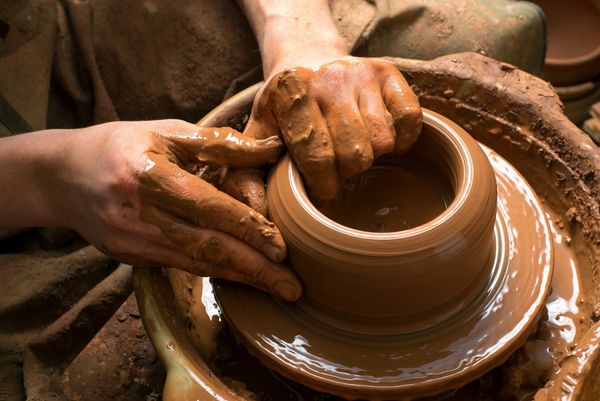The potters hands form clay on the wheel. Dark clay for a rich color finish. A long process of art.