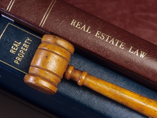Wooden gavel resting on books about real estate law and property.