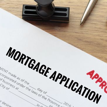 A Mortgage Application on a wooden table that has been stamped APPROVED.