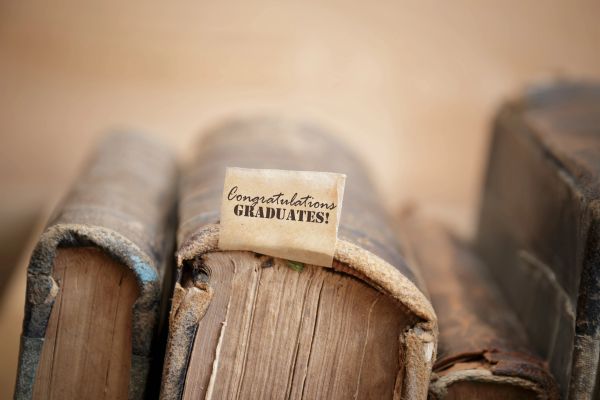 Old books with a note saying "Congratulations Graduates!" on top.