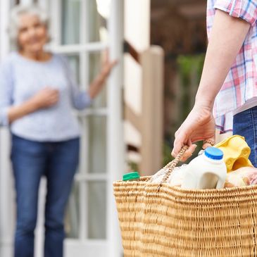 A carer bringing groceries to an elderly woman