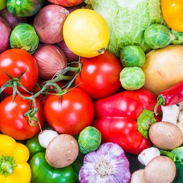 A colorful assortment of fresh vegetables and a lemon.