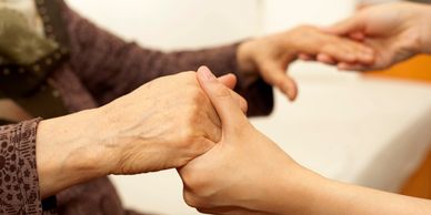 An individual of middle age offering a supportive grip to an elderly person.