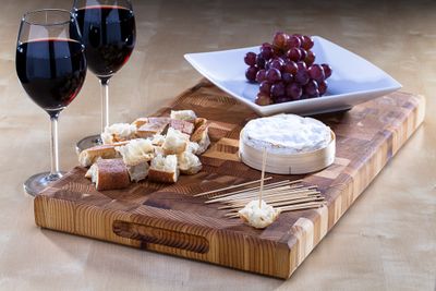 selection of french cheeses with some french black grapes and two glasses of french red wine 