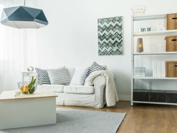 A cozy white living room with a couch, geometric cushions, and modern decor.