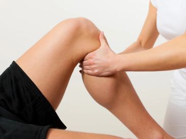 Physical therapist examining a person's knee for injury or pain.