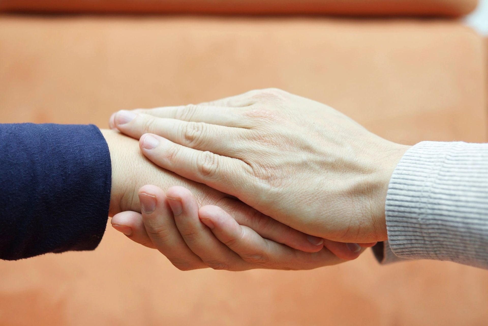 Two hands gently holding each other in a comforting gesture.