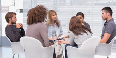 a group of people sitting in chairs in a discussion circle