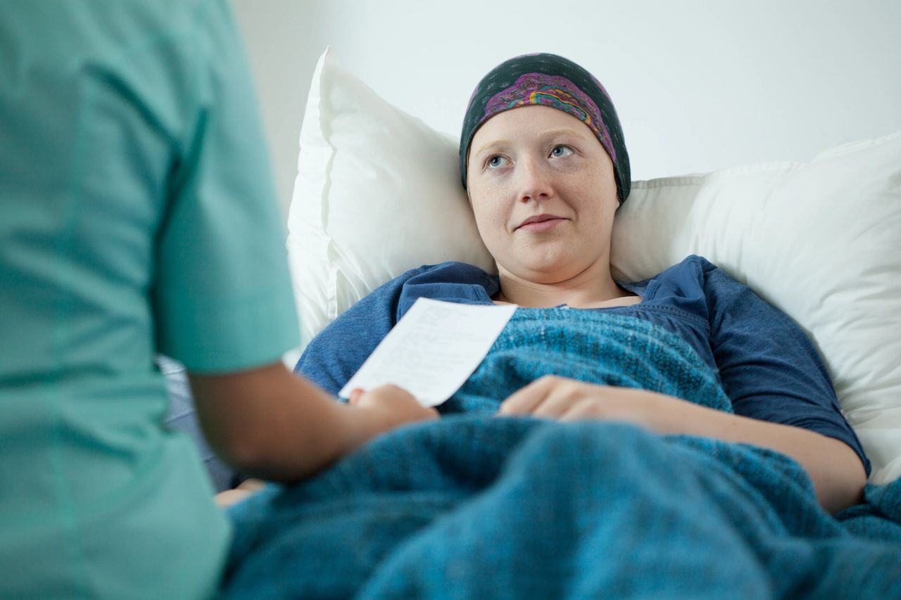 A female patient with a headscarf looking up at a nurse.