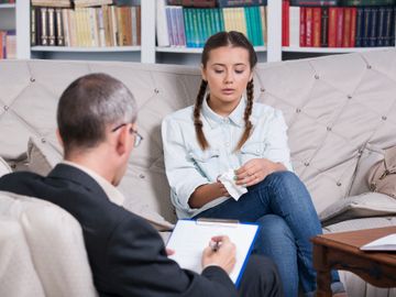 A young woman talks to a therapist in a cozy office.