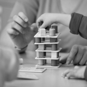 A child and adult playing a stacking game with blocks.