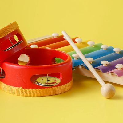 On a yellow background, a colourful xylophone sits behind and two red and yellow tambourines 