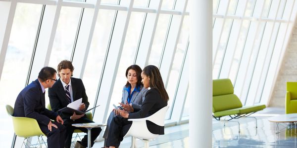 two men two women all sitting next  to a wall of glass having a discussion