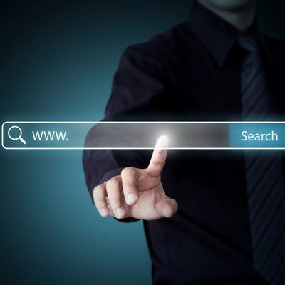 Businessman touching a glowing online search bar with 'www.' and search button.