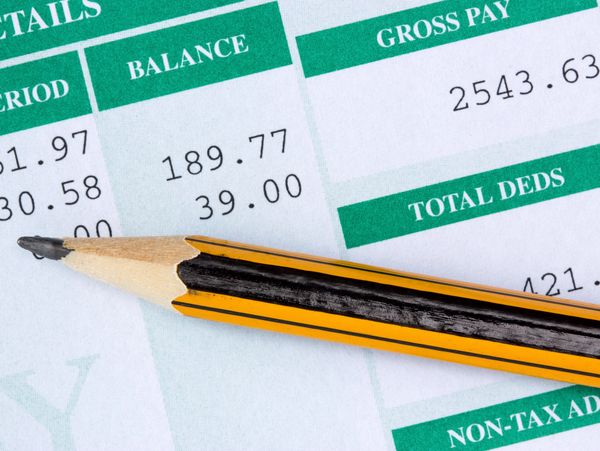 A sharpened pencil resting on a financial document with figures and headings.
