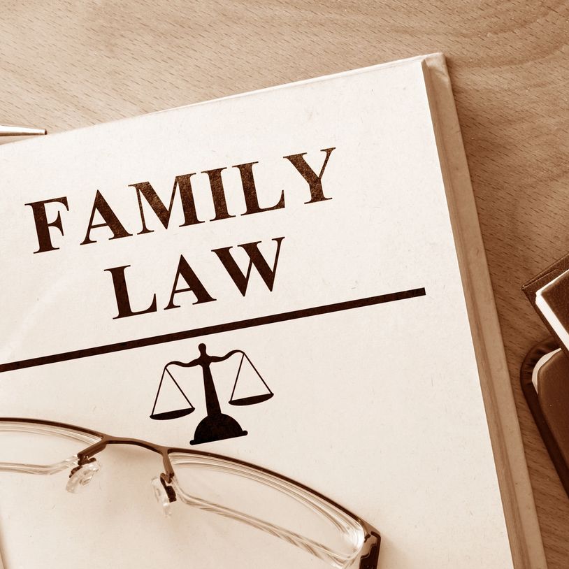 Family law book with glasses on a wooden table.