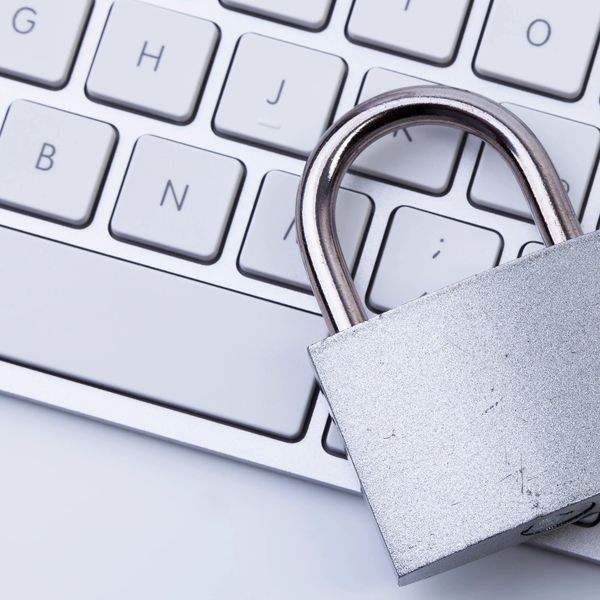 A silver padlock resting on a white computer keyboard.
