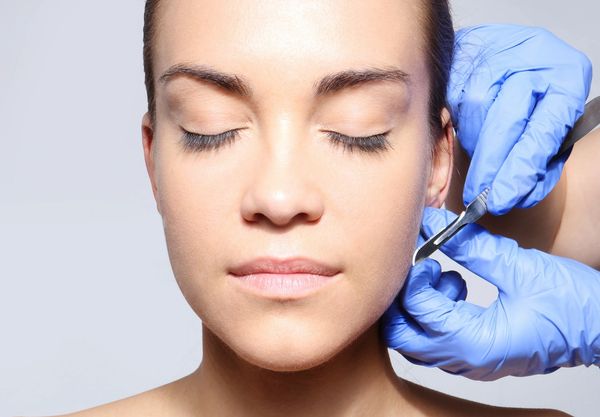Woman receiving a cosmetic injection on her cheek with closed eyes.