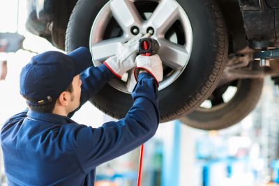 Mechanic working on car wheel in a garage.