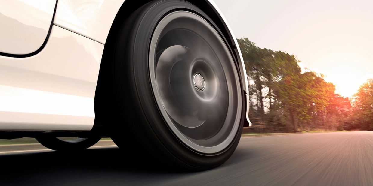Close-up of a spinning car wheel on a road at sunset.
