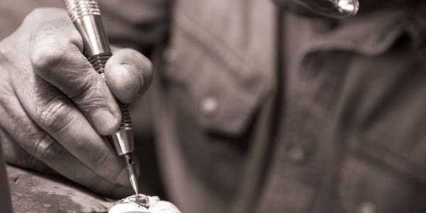 Jeweler using tool to work on piece.